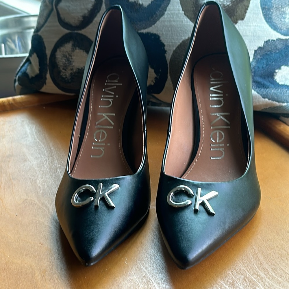 Calvin Klein black pumps with silver CK emblem on front of shoe. NWT size 10